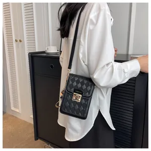 Detailed view of black quilted mini phone bag with gold clasp and fashion text