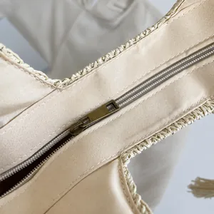 Detail of smooth bronze metal zipper and handwoven paper straw texture on a beach bag