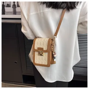 Detail of quilted crossbody phone bag with gold clasp and cartoon cow charm accessory
