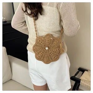 Detail of hand-crocheted khaki flower bag with pearl button and tassel on a model
