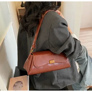 Dettaglio della borsa baguette marrone vintage con fibbia dorata e tracolla in pelle