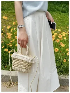 Detail of straw woven bucket bag with lace ruffles and pearl accents in a park setting