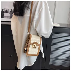 Close-up of quilted crossbody phone bag with cow charm on model in oversized white shirt