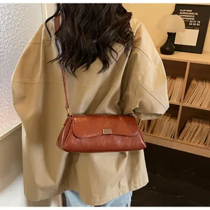 Dettaglio della borsa vintage in pelle marrone indossata a tracolla in interni accoglienti