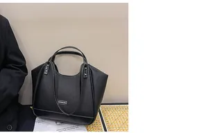 Détail du sac cabas en cuir noir avec coutures contrastées blanches et logo argenté