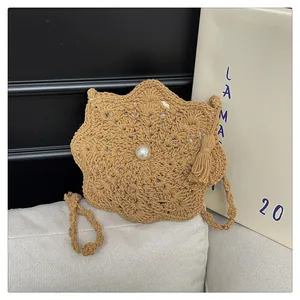 Detail of star-shaped straw shoulder bag with pearl decor and hanging tassels