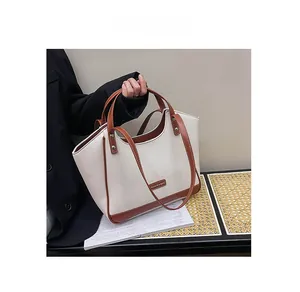 Détail du sac cabas en cuir grainé blanc crème avec lanières marron et plaque en métal