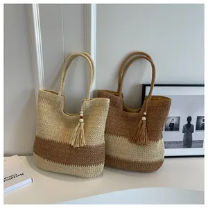 Detail of woven straw tote bags with two-tone design and decorative tassel charms