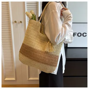 Close-up of woven straw tote bag with bicolor paper rope texture and tassel detail