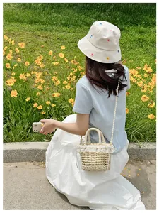 Detail of straw bucket bag featuring white lace trim, pearls, and drawstring lining