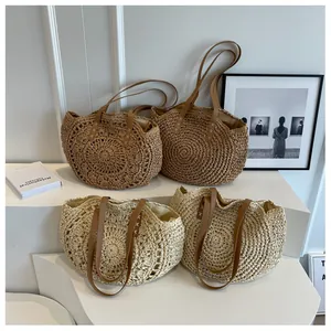 Detalle de bolsos tote de paja hechos a mano en beige y caqui con asas de cuero marrón