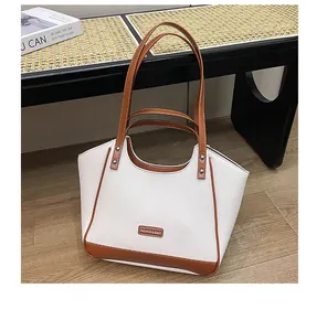 Détails du cabas en cuir grainé blanc avec anses marron et finitions rivetées