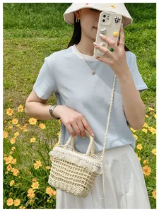 Detailed view of beige woven straw bag with white lace trim and elegant pearl accents
