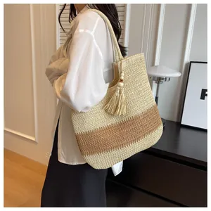Detail of woven straw tote bag with dual-tone texture and stylish tassel decoration