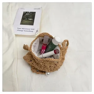 Handmade woven straw shoulder bag with inner lining and pearl detail for beach vacation