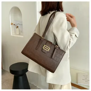 Close-up of a dark brown crocodile embossed tote bag with elegant gold buckle hardware