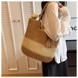Detail shot of woven straw tote bag with brown beige stripes and tassel pendant on model