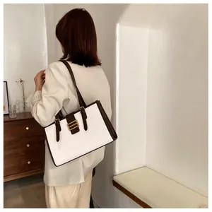 Close-up of white croc-embossed leather tote bag with brown straps and gold buckle detail