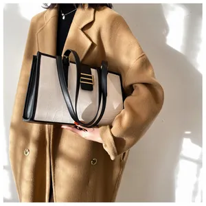 Detail of white crocodile embossed leather tote with golden buckle and black trim edges
