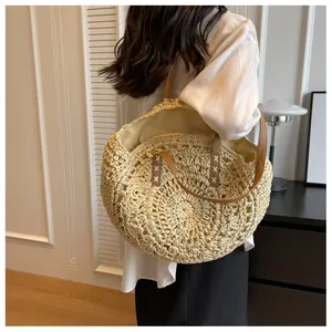 Detalle de bolso tote de paja hecho a mano con correas de cuero marrón y costuras en X