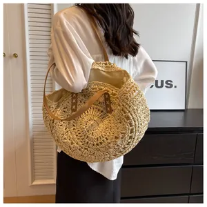 Detalle de bolso tote de paja trenzada con correas de cuero marrón y costuras decorativas