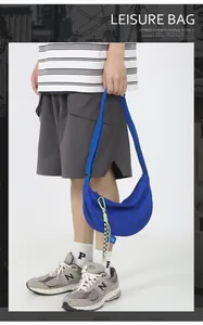 Detail van een blauwe nylon halve maantas met dambordpatroon en geweven koord aan de rits