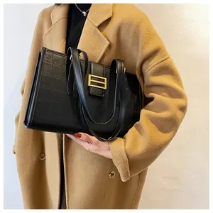 Close-up of black croc-effect tote bag with gold metal buckle and dual shoulder straps