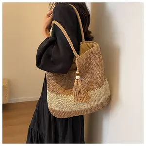 Detail of woven straw tote bag with tricolor patchwork pattern and tassel pendant