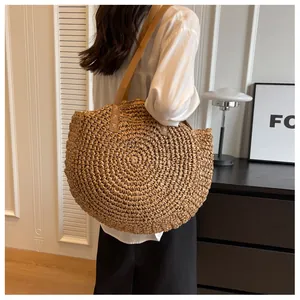 Detalle de bolso tote de paja con tejido radial y correa de hombro de cuero fino