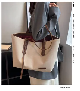 Detail of canvas tote bag with brown leather handles and brand label on model