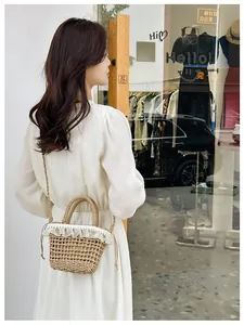 Detail of straw bucket bag featuring white lace trim and faux pearl accents on the rim