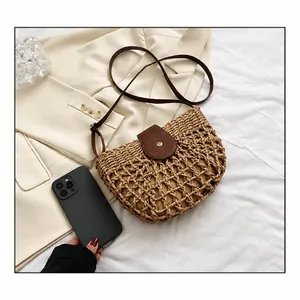 Close-up of hollowed-out straw shoulder bag with leather flap and smartphone for size scale