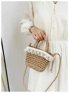 Close-up of the woven straw bucket bag with delicate white lace and pearl trim detail