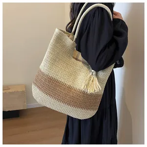 Detail view of woven straw tote bag with brown gradient colors and stylish tassel