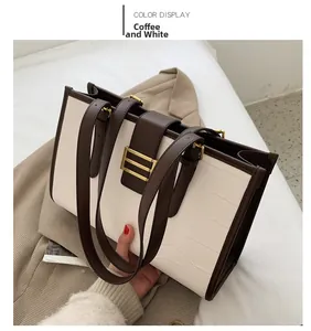 Detail of coffee and white tote bag with faux crocodile pattern and gold buckle