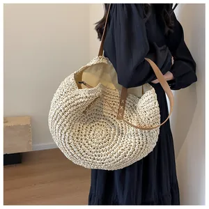 Detalle del bolso de paja con correa de cuero marrón y costuras refinadas en X
