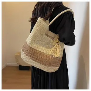Detail of woven straw tote bag featuring two-tone stripes and stylish tassel ornament