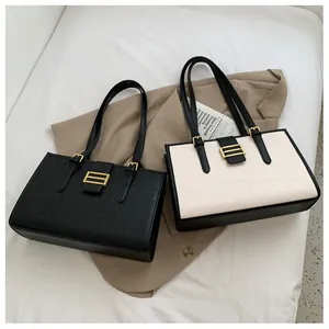 Detailed view of crocodile pattern texture on black and cream faux leather tote bags