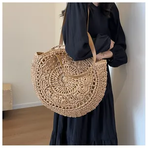Detalle de un bolso tote redondo de paja tejida con asas marrones de estilo bohemio