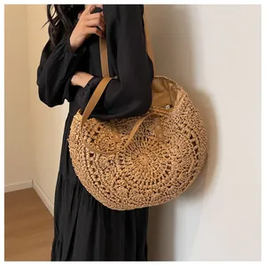 Detalle de un bolso tote grande de paja con correas de cuero marrón y tejido rústico