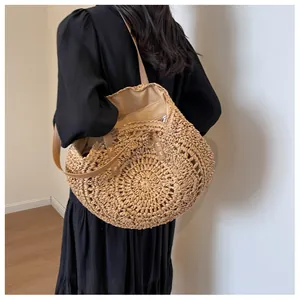 Detalle del bolso tote redondo de paja con asas de cuero marrón y patrón tejido calado