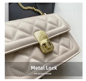 Vue détaillée du fermoir doré et du cuir beige matelassé sur le sac à bandoulière
