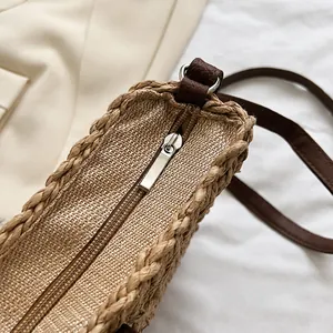 Detail of a smooth silver zipper closure on a straw woven crossbody shoulder bag