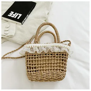 Detail of straw woven bucket bag with lace trim, pearl accents and crossbody strap