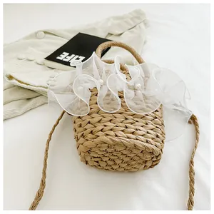 Detail of straw woven bucket bag with white organza ruffles and pearls on a white sheet