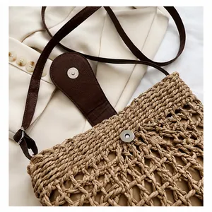Detailed macro view of the hardware magnetic buckle on a straw woven crossbody bag