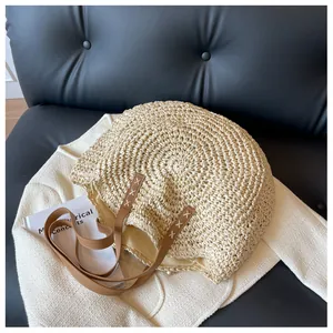 Detalle del bolso de paja con asas de cuero marrón y costuras en X blancas decorativas