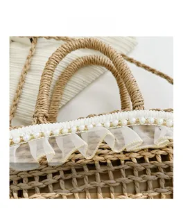 Detailed close-up of woven straw bag with white lace trim and pearl embellishments