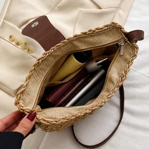 Detail of straw crossbody bag showing internal capacity with phone, wallet and cosmetics