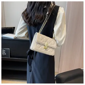 Gros plan sur le sac matelassé beige avec bandoulière chaîne dorée et fermoir pivotant